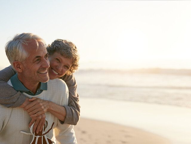 Smiling senior couple embraces while walking along a scenic beach