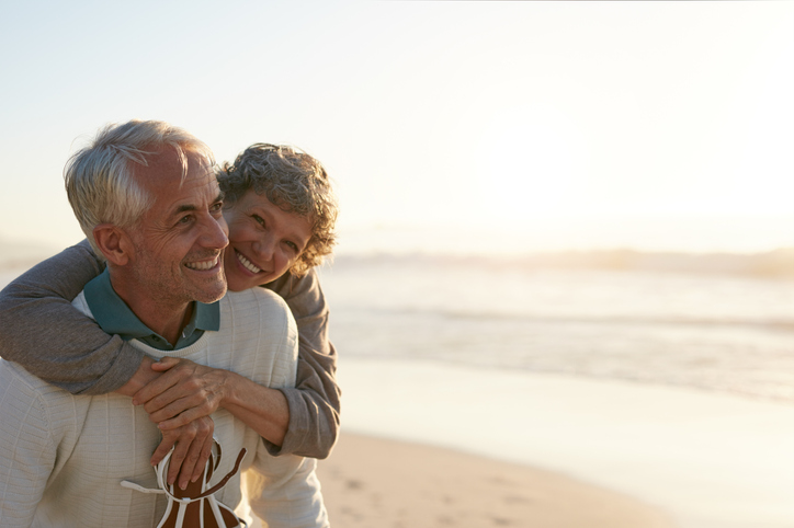 Smiling senior couple embraces while walking along a scenic beach