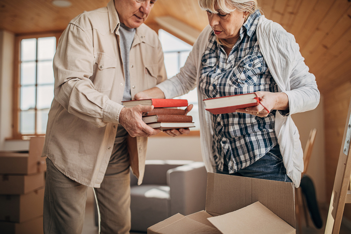 Two people, senior married couple unpacking boxes in their new apartment..