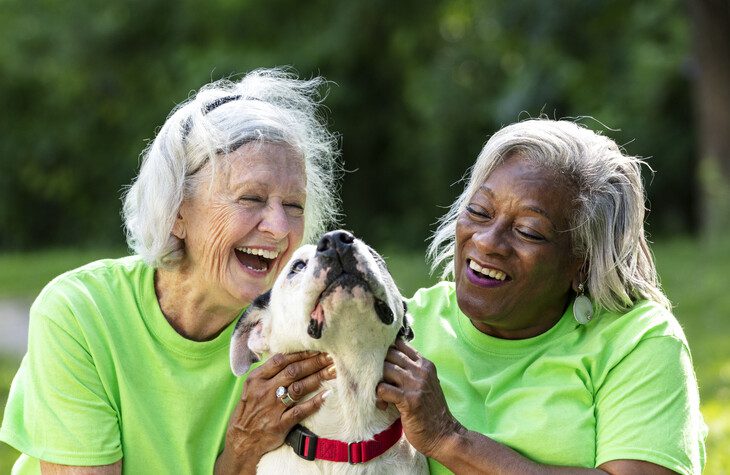 Two older women volunteering their time with a rescue dog.