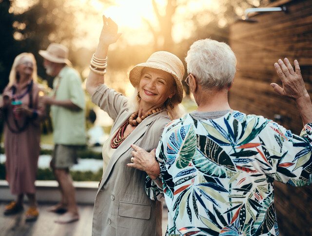 Carefree senior couple dancing on a party in the backyard at sunset.